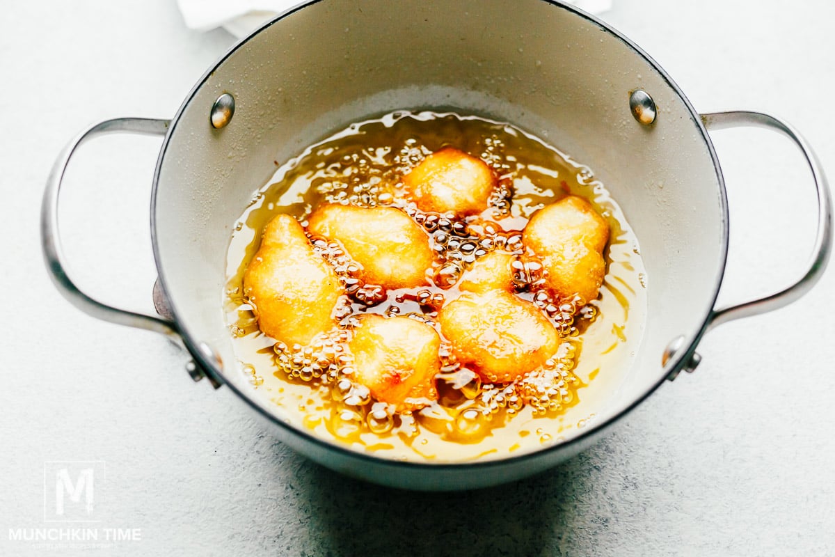 Chicken deep frying inside the pan filled with oil.