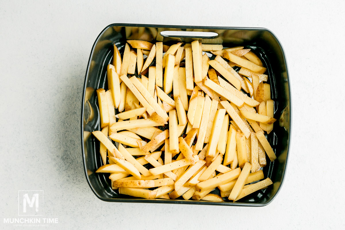 French fries placed into air fryer pan.