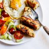Chicken and mushroom sausages on a plate with salad and egg.