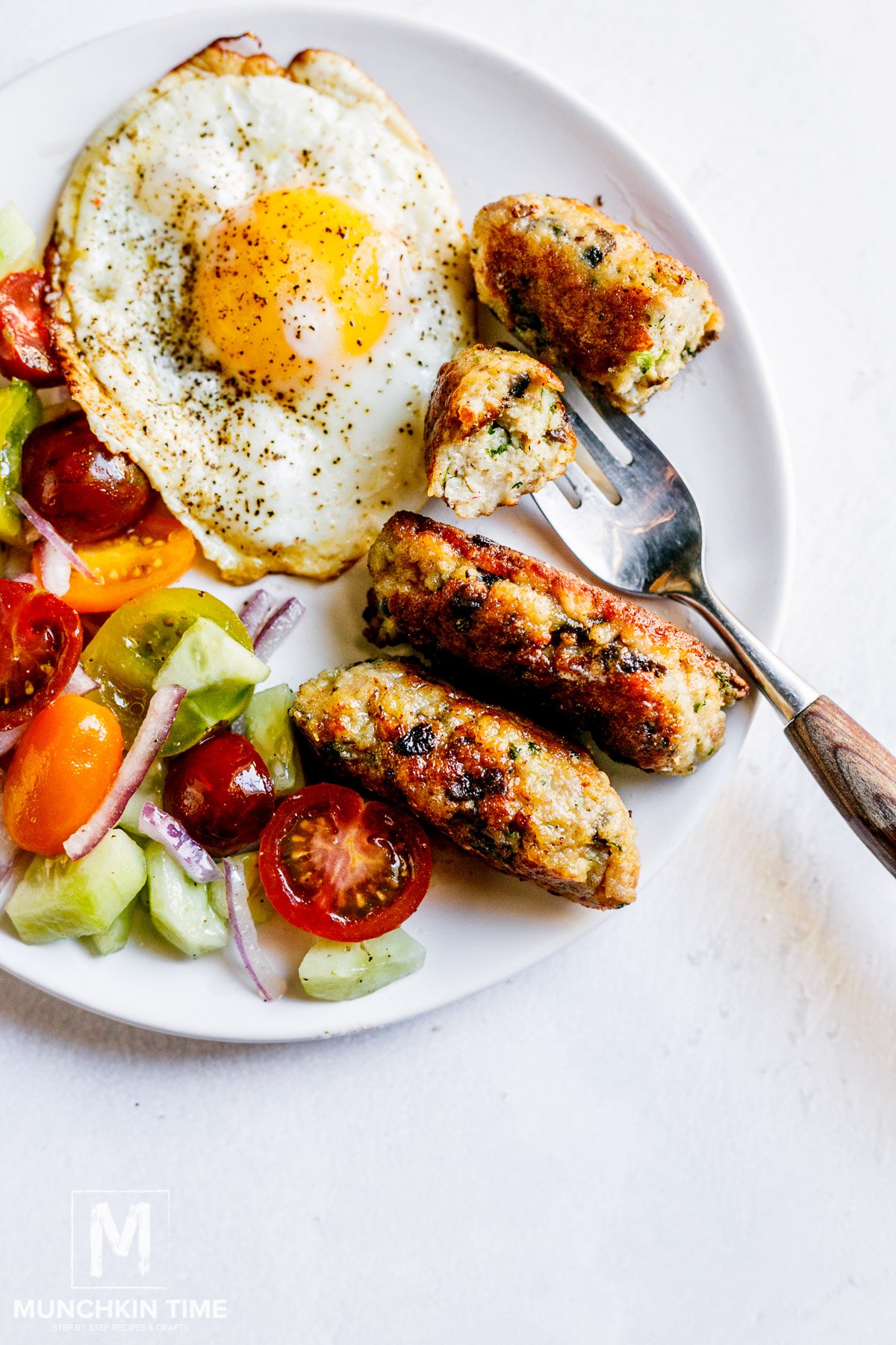 Chicken and mushroom sausages on a plate with salad and egg.