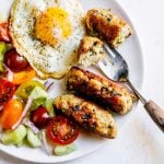 Chicken and mushroom sausages on a plate with salad and egg.