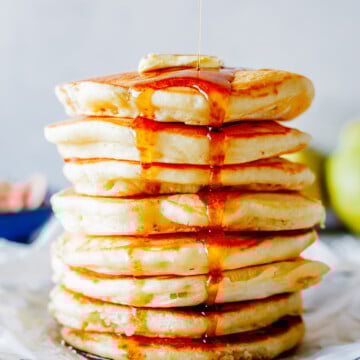 fluffy buttermilk pancakes and maple syrup being poured over the top.