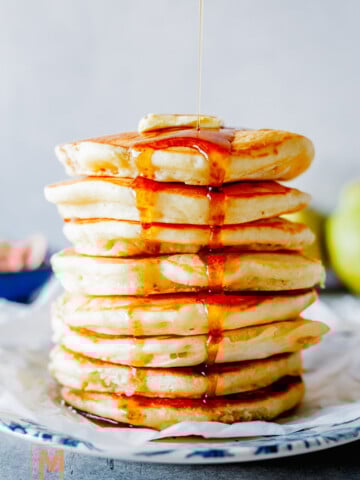 fluffy buttermilk pancakes and maple syrup being poured over the top.