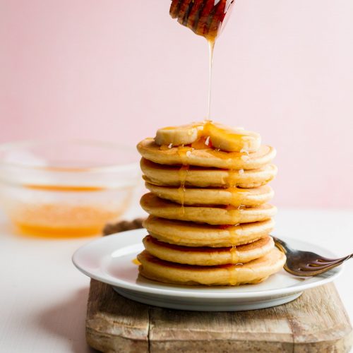 Quick & Easy Buttermilk Pancake Recipe with honey drizzle and banana slices.
