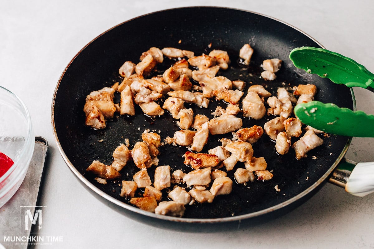 Chicken pieces sautéing in the skillet.