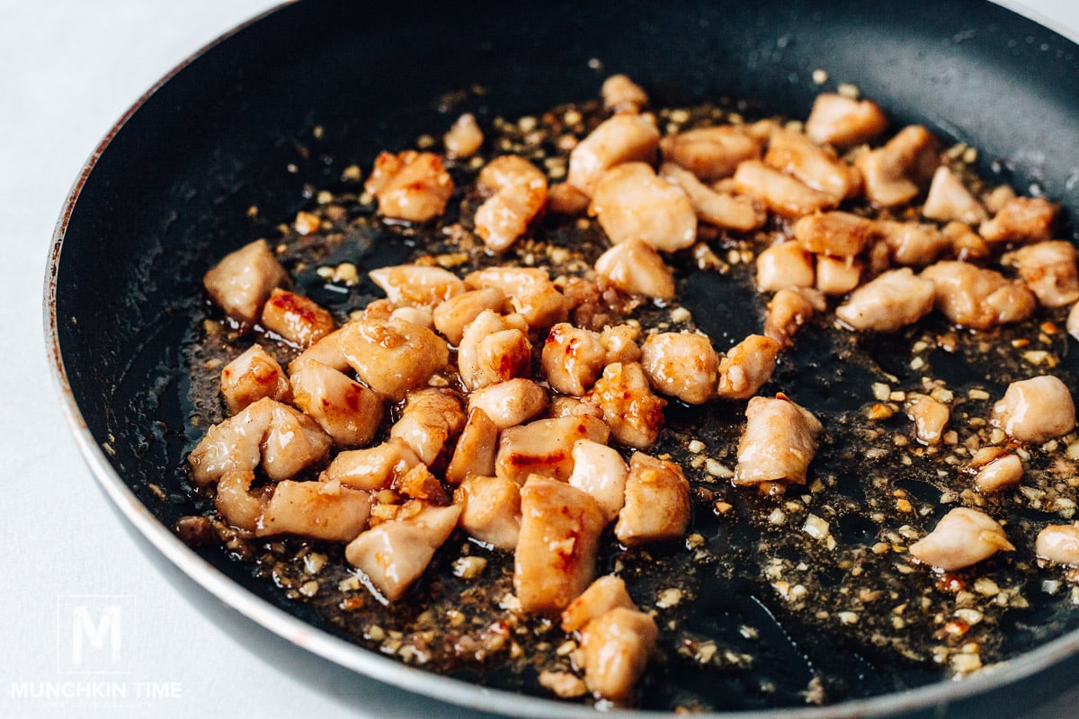 Chicken pieces sautéing in the skillet with garlic sauce.