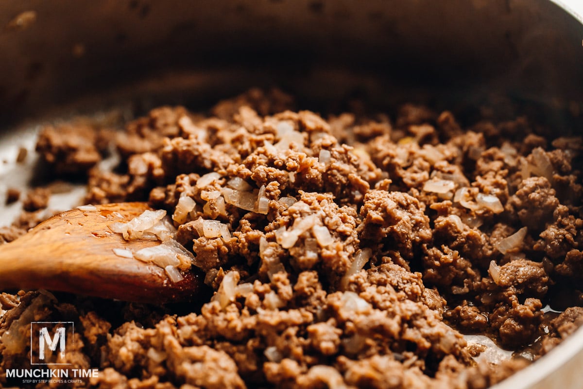 Cooked ground beef sauteed with onion inside the skillet.