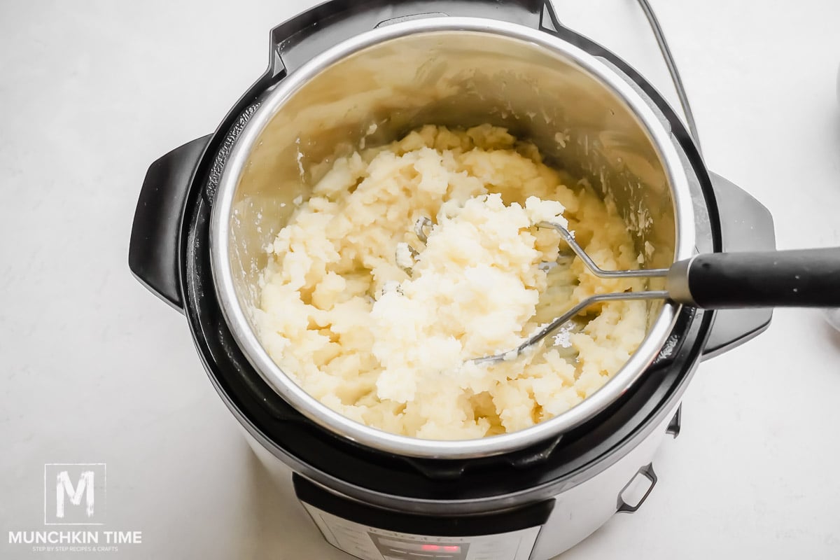 Potato mashed with potato masher inside instant pot.