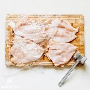Pounded chicken breast on a cutting board.