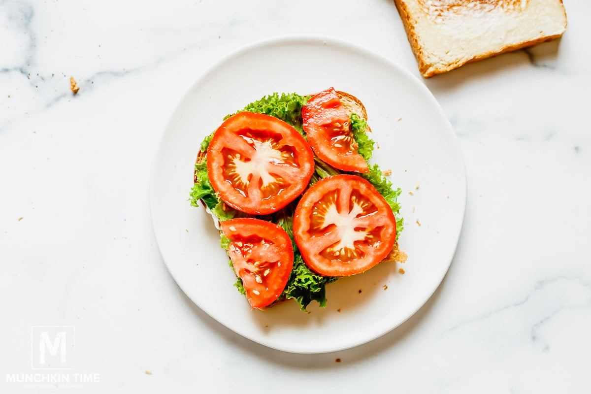 Lettuce and tomato slices on a slice of bread.