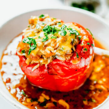 Stuffed Bell Peppers cooked in Instant Pot served on a plate over red sauce.