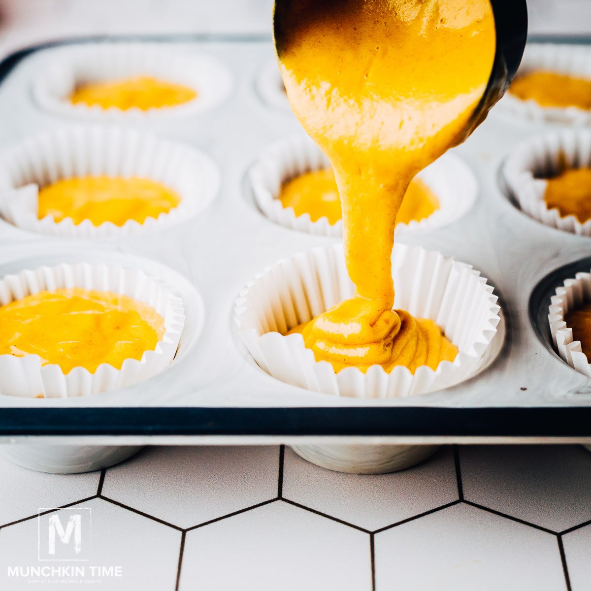 Pumpkin Muffin Batter pouring into the muffin cups.