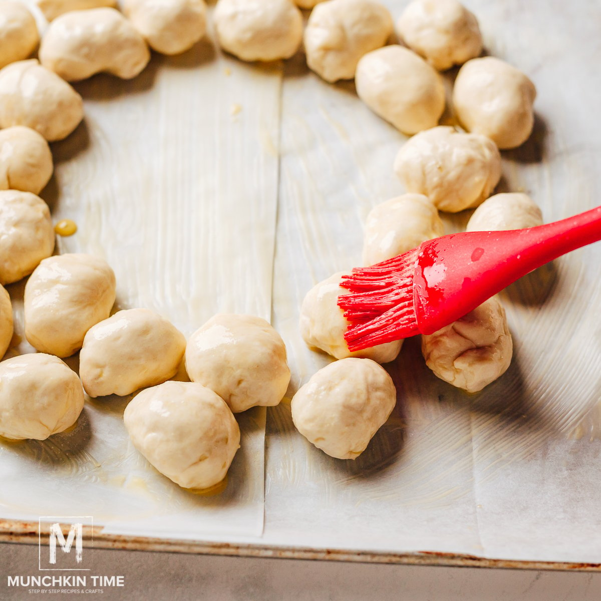 Brushing egg wash over pizza rolls.