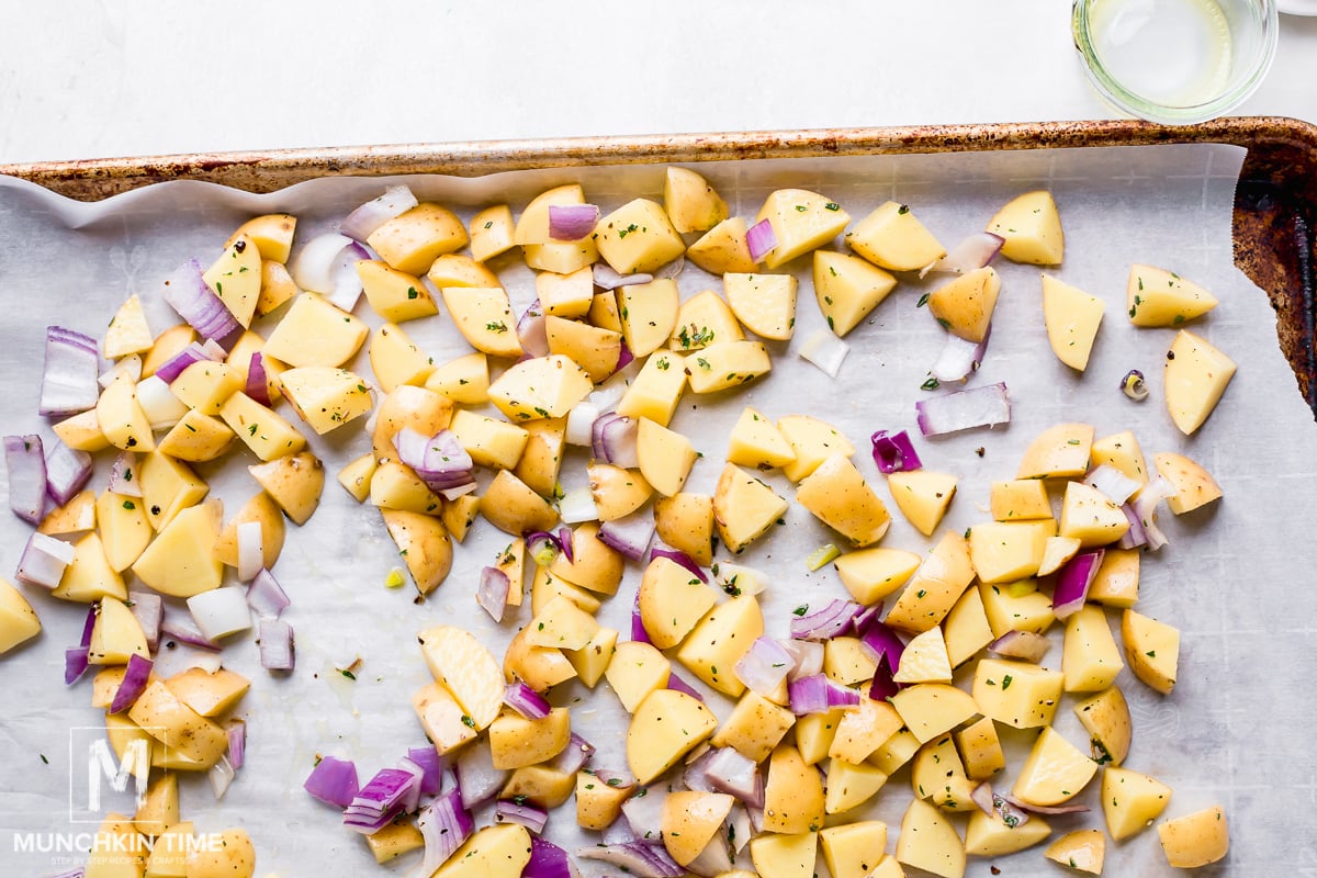 Roast the seasoned potatoes and red onion on a baking sheet for 10 minutes.