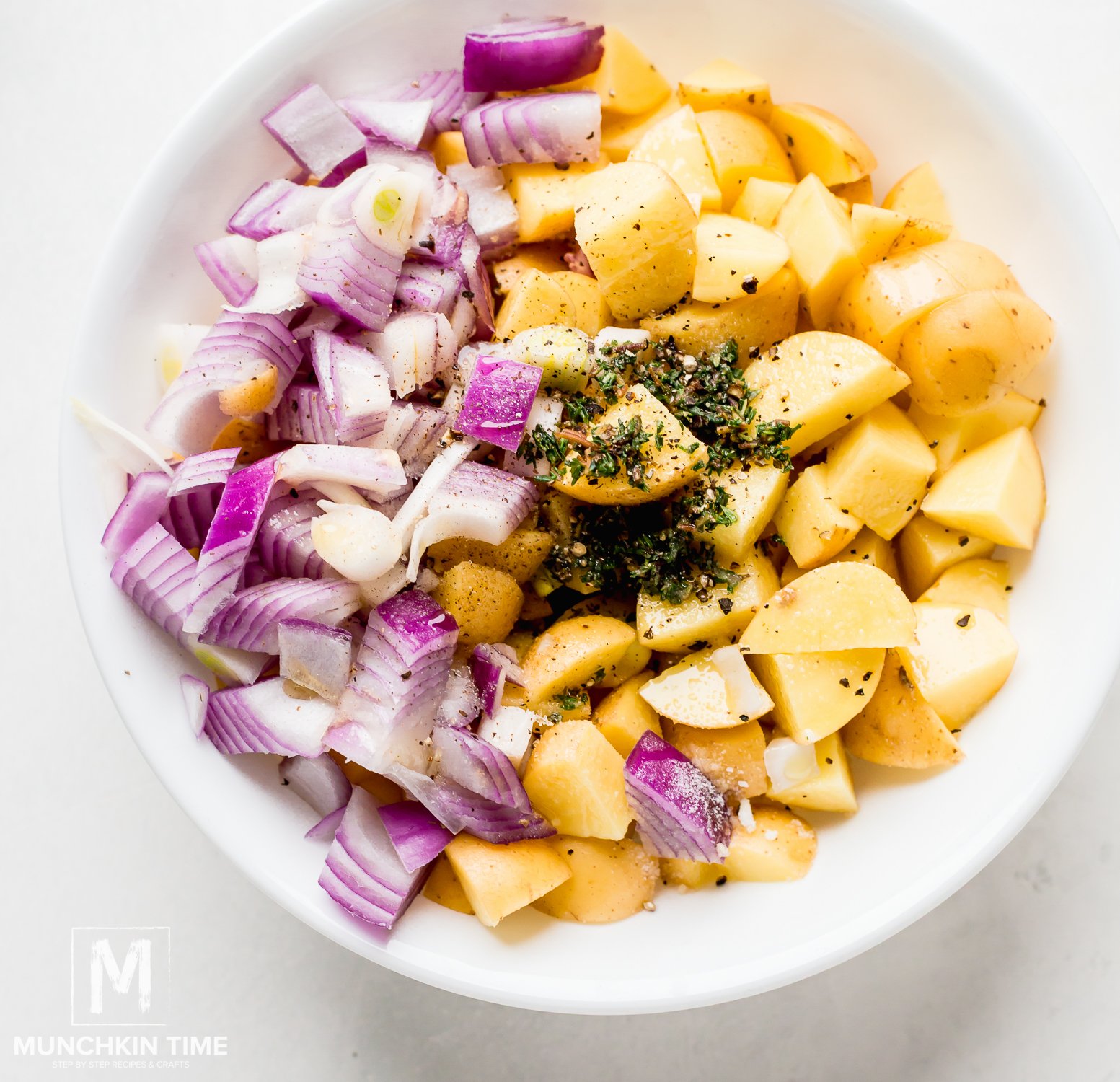 Roast the seasoned potatoes and red onion on a baking sheet for 10 minutes.