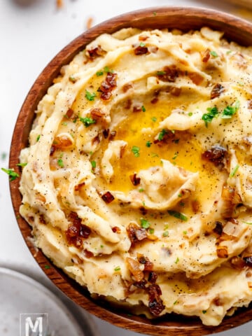 mashed potatoes with caramelized onions and cheese garnished with chopped parsley and melted butter