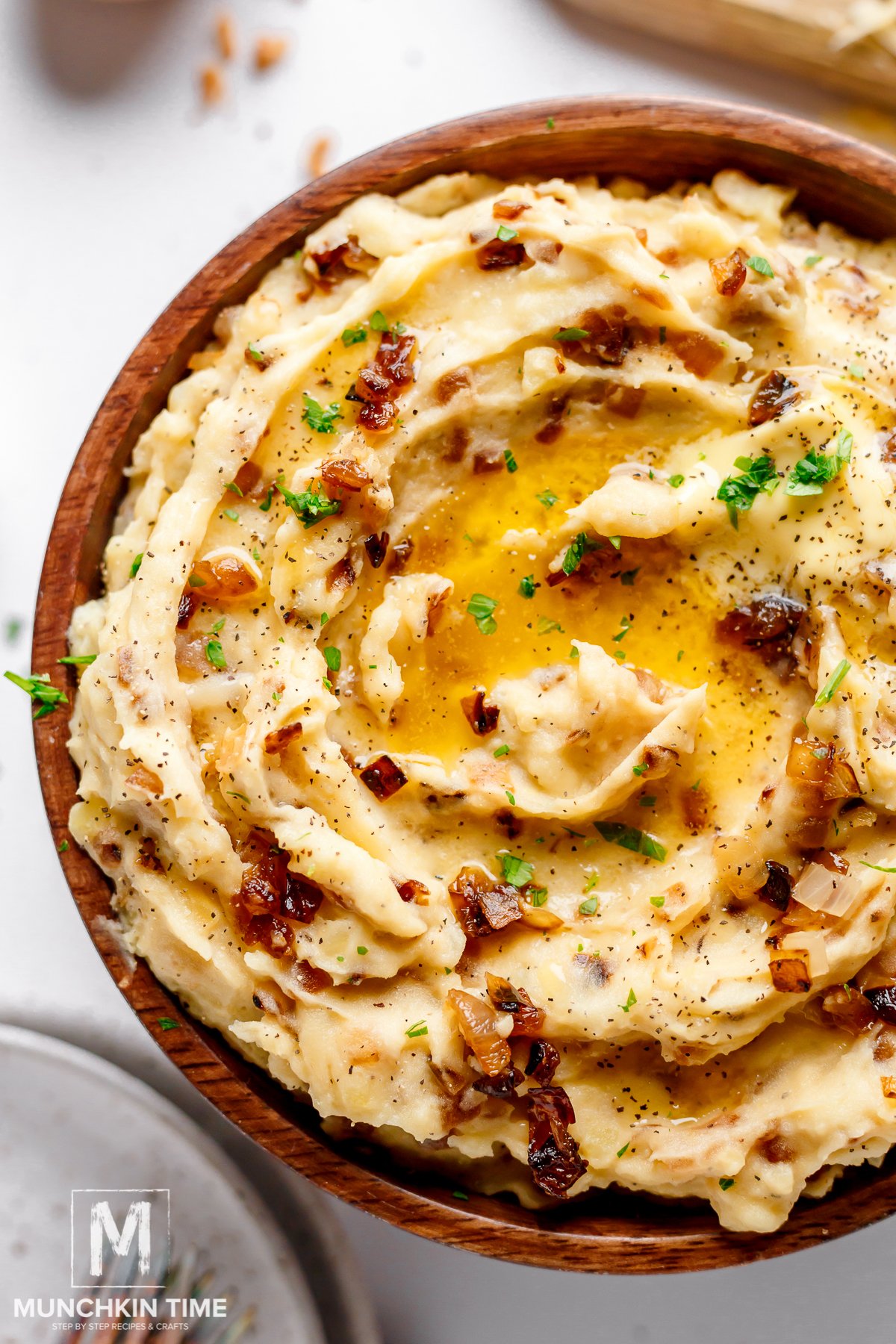 mashed potatoes with caramelized onions and cheese garnished with chopped parsley and melted butter