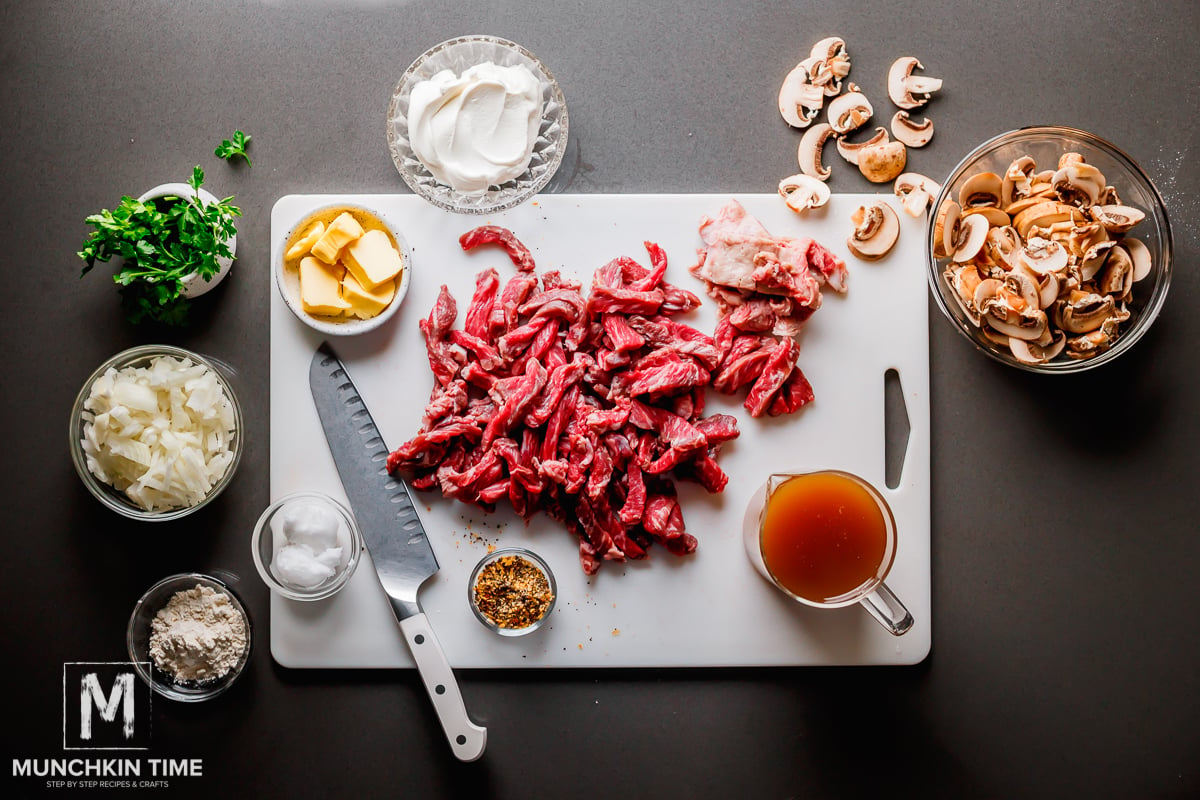 top view of ingredients new york steak, mushrooms, onion, broth, sour cream, butter, flour and seasonings. 