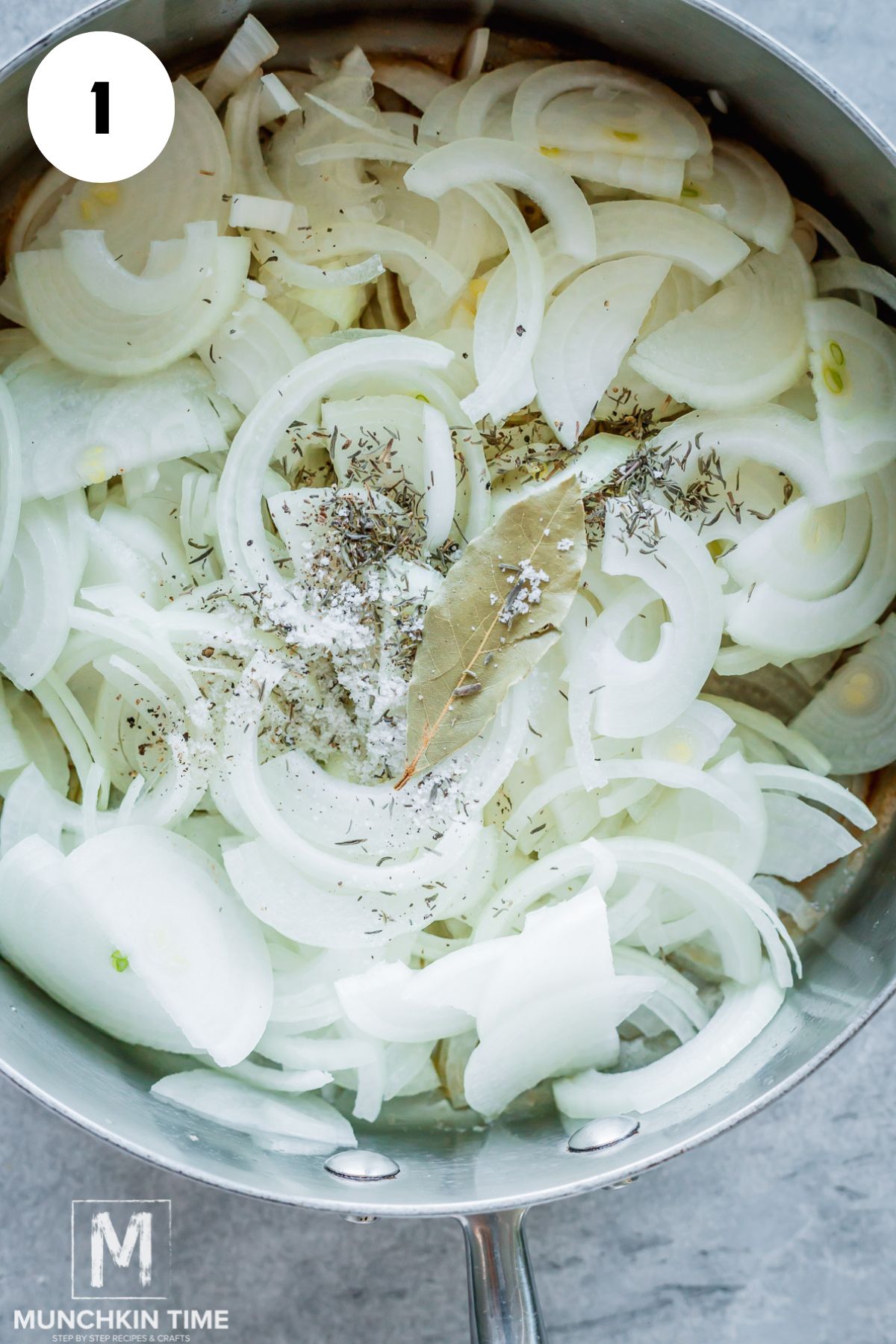 sliced onions with bay leave and spices added to the skillet.