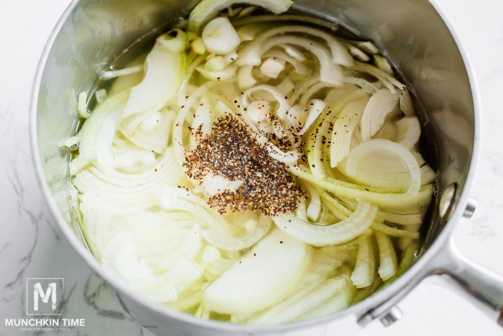 onion and chicken broth with black pepper in a sauce pot