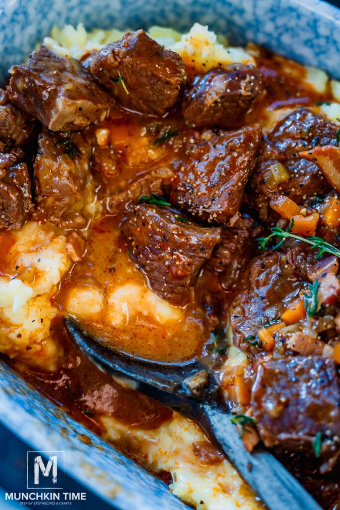 Guinness Beef Stew over mashed potatoes and a wooden spoon