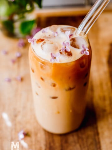 Protein Coffee with ice in a tall glass with glass straw.