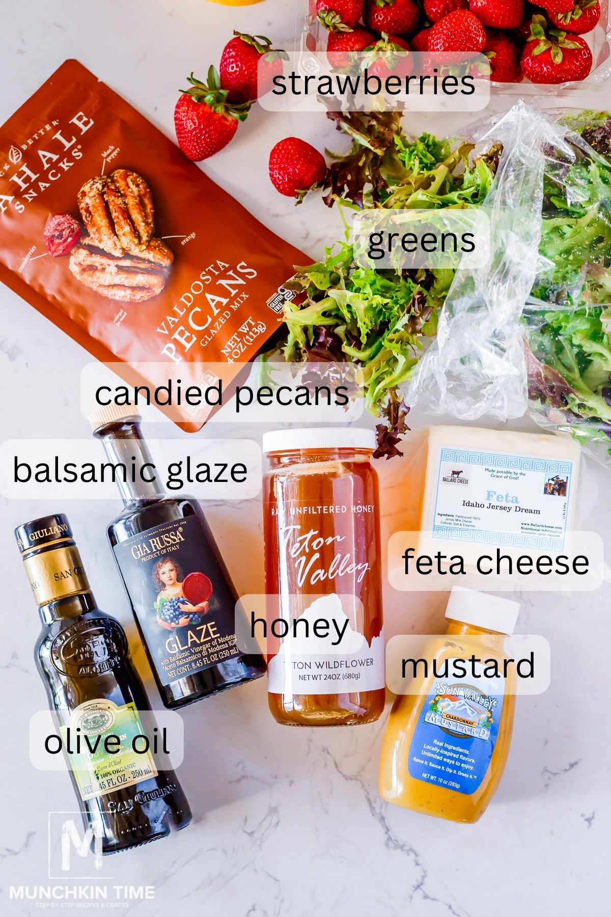 Ingredients on the table - strawberries, greens, feta cheese, pecans, salsamic glaze, olive oil, honey and mustard. 