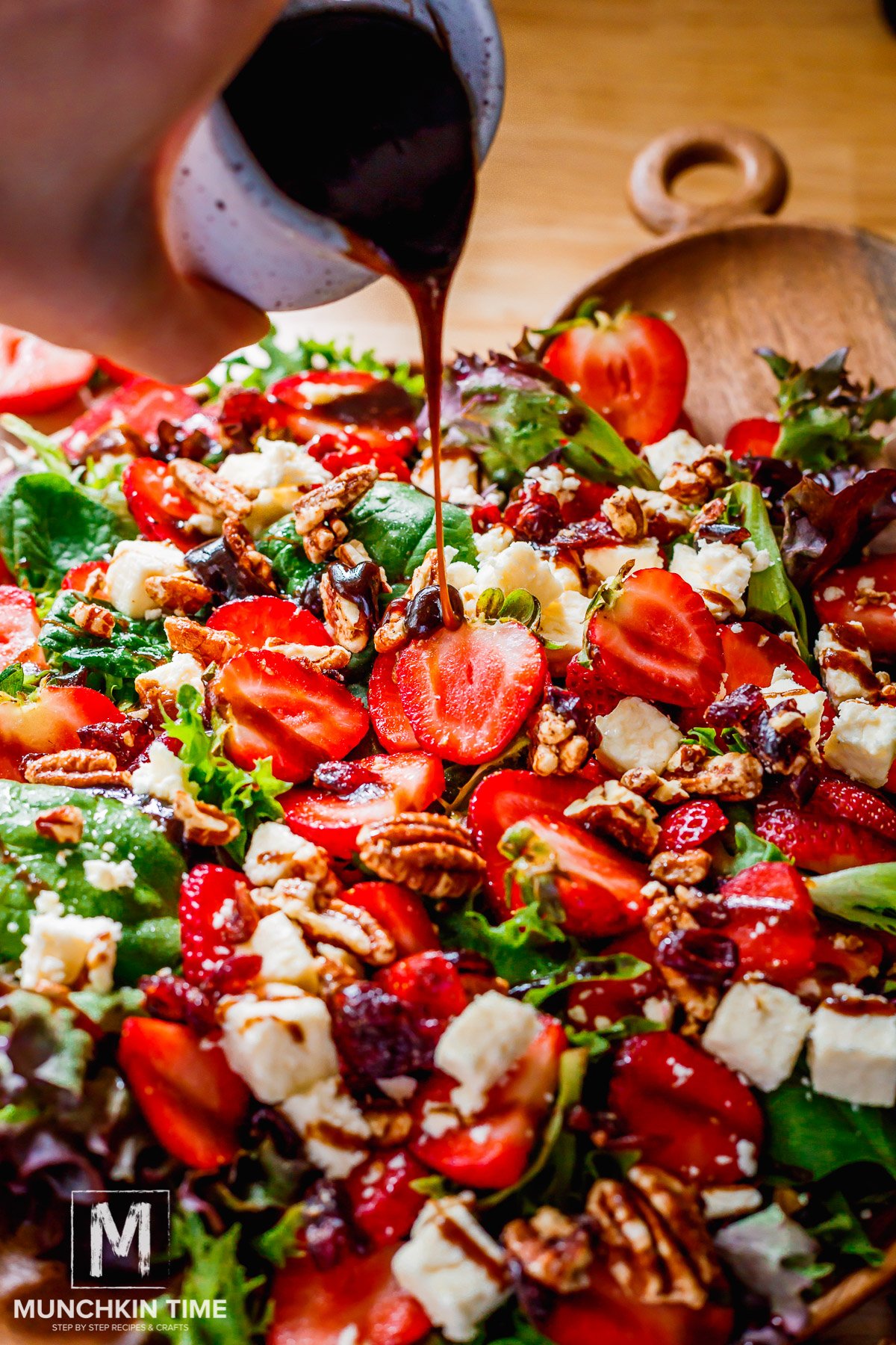 Balsamic dressing being poured over Spinach Strawberry Salad with Pecans.