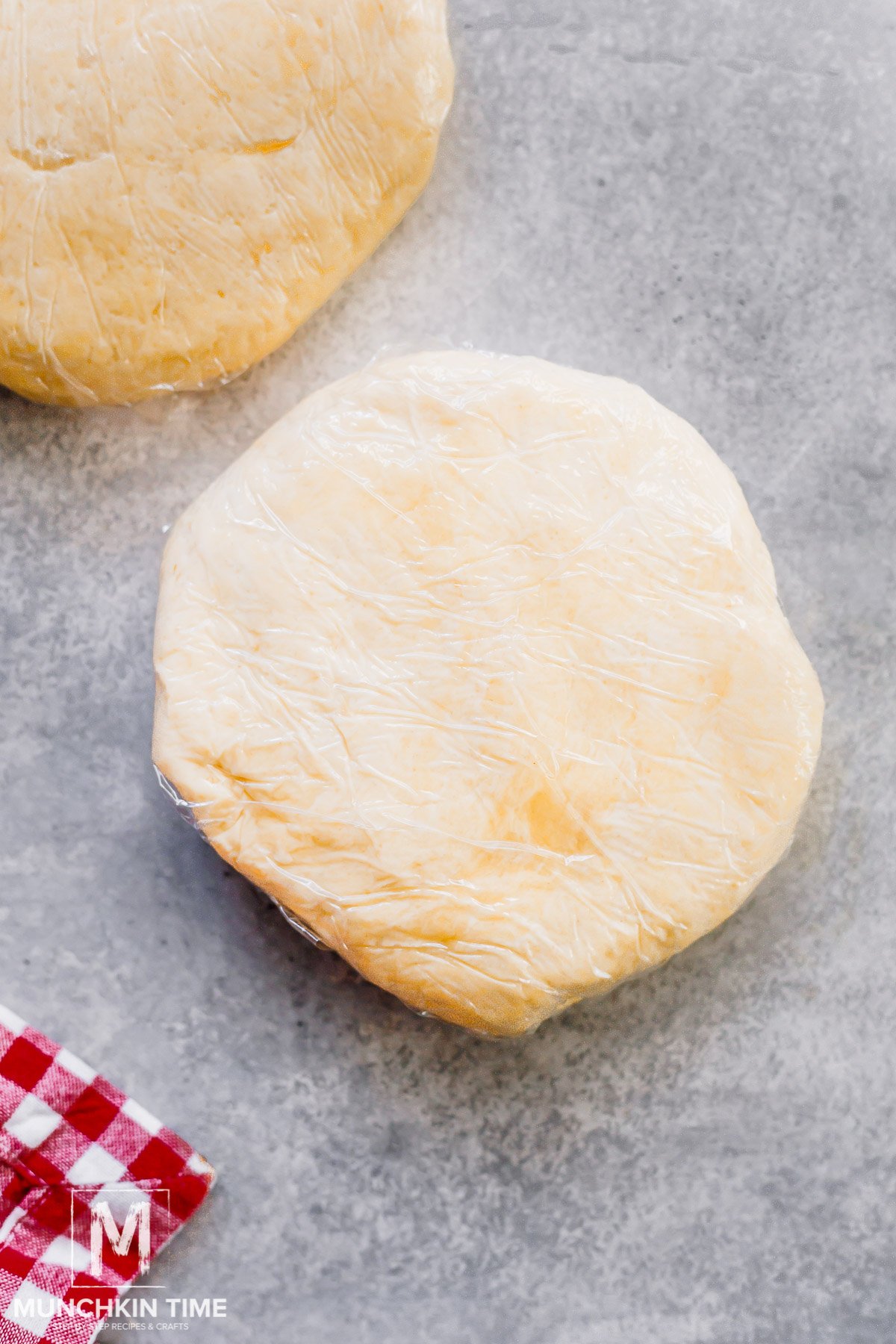 a dough flattened into a disc and wrapped with plastic wrapper.