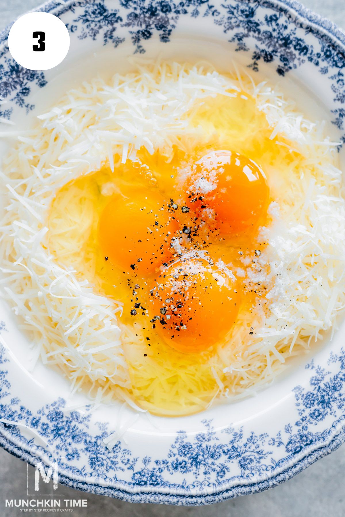 Parmesan cheese with eggs and seasoning in a blue bowl.
