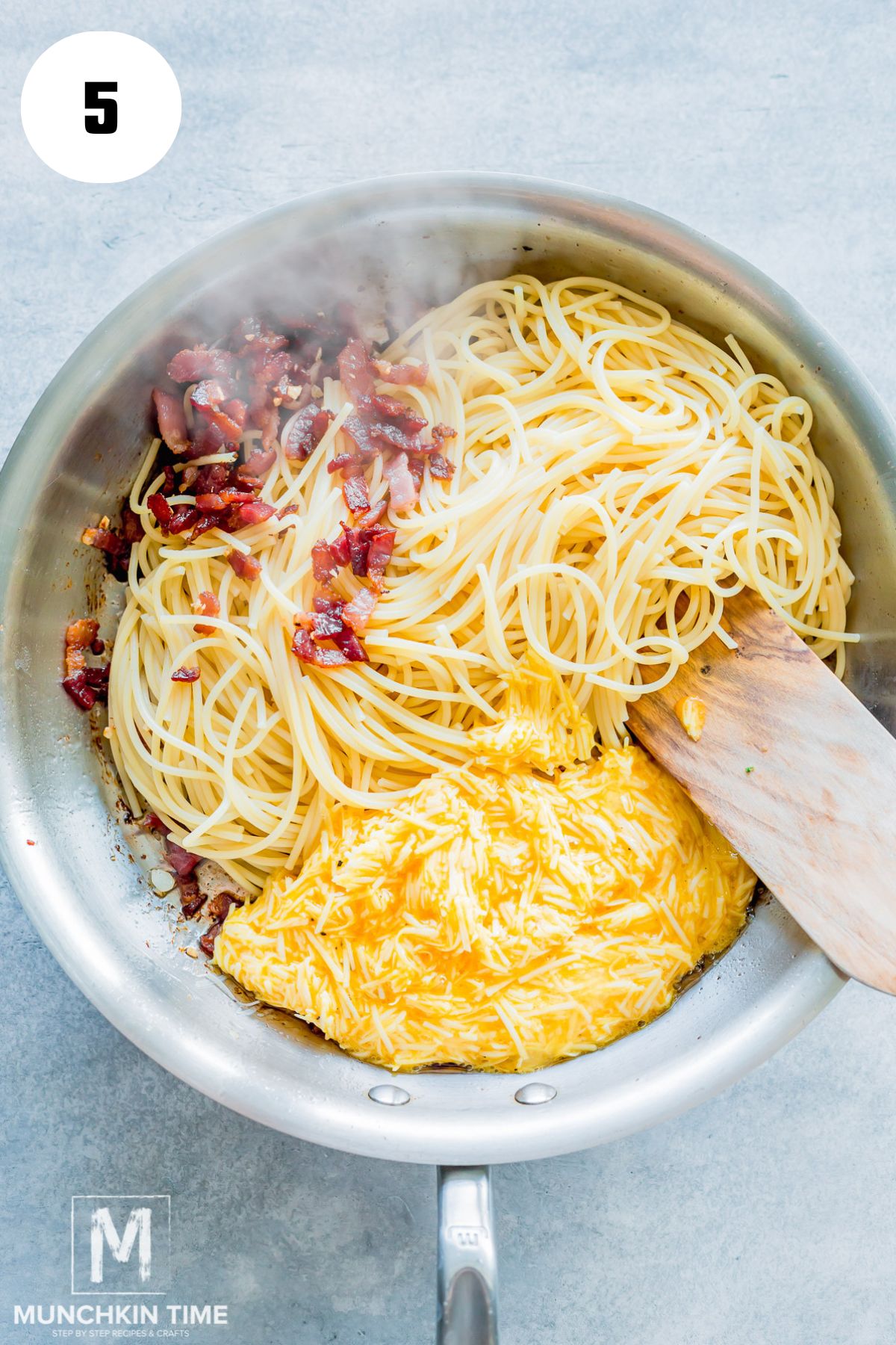 cooked bacon and pasta in the skillet with egg and cheese mixture.