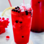 Huckleberry Lemonade in a tall glass with ice and huckleberry berries.