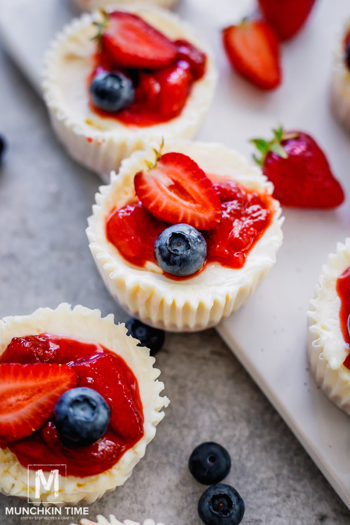 A delicious summer dessert - No Bake Mini Cheesecake with strawberry sauce and blueberry garnish.