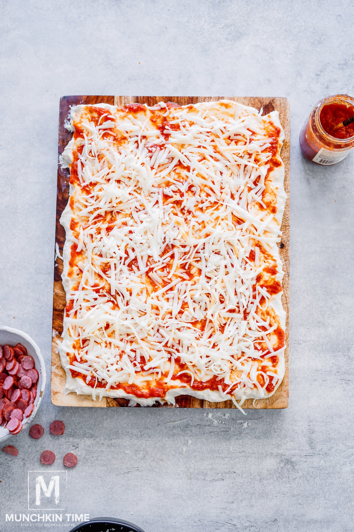 cheese spread over the dough with pizza sauce.
