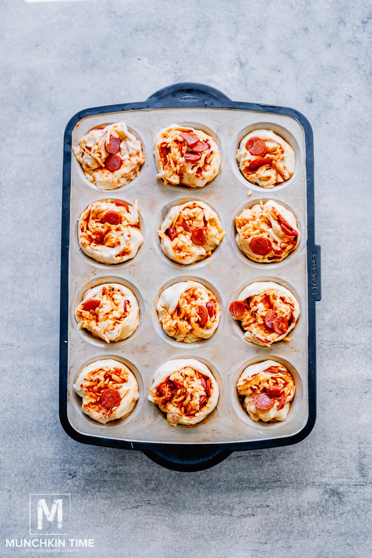 sourdough rolls with pizza filling inside the muffin pan.