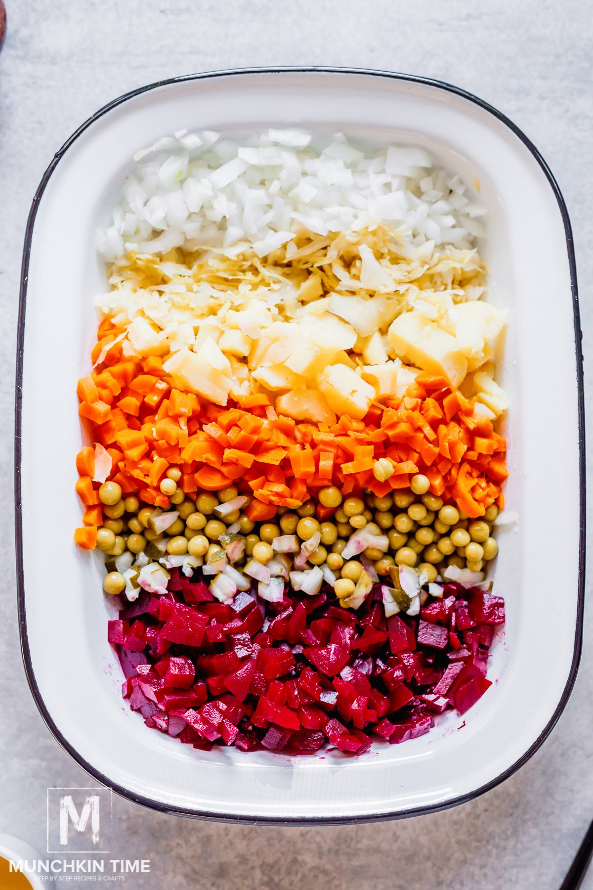 Cooked potato, beets and carrots diced and added to the bowl with sauerkraut, pickles, onion, and peas.
