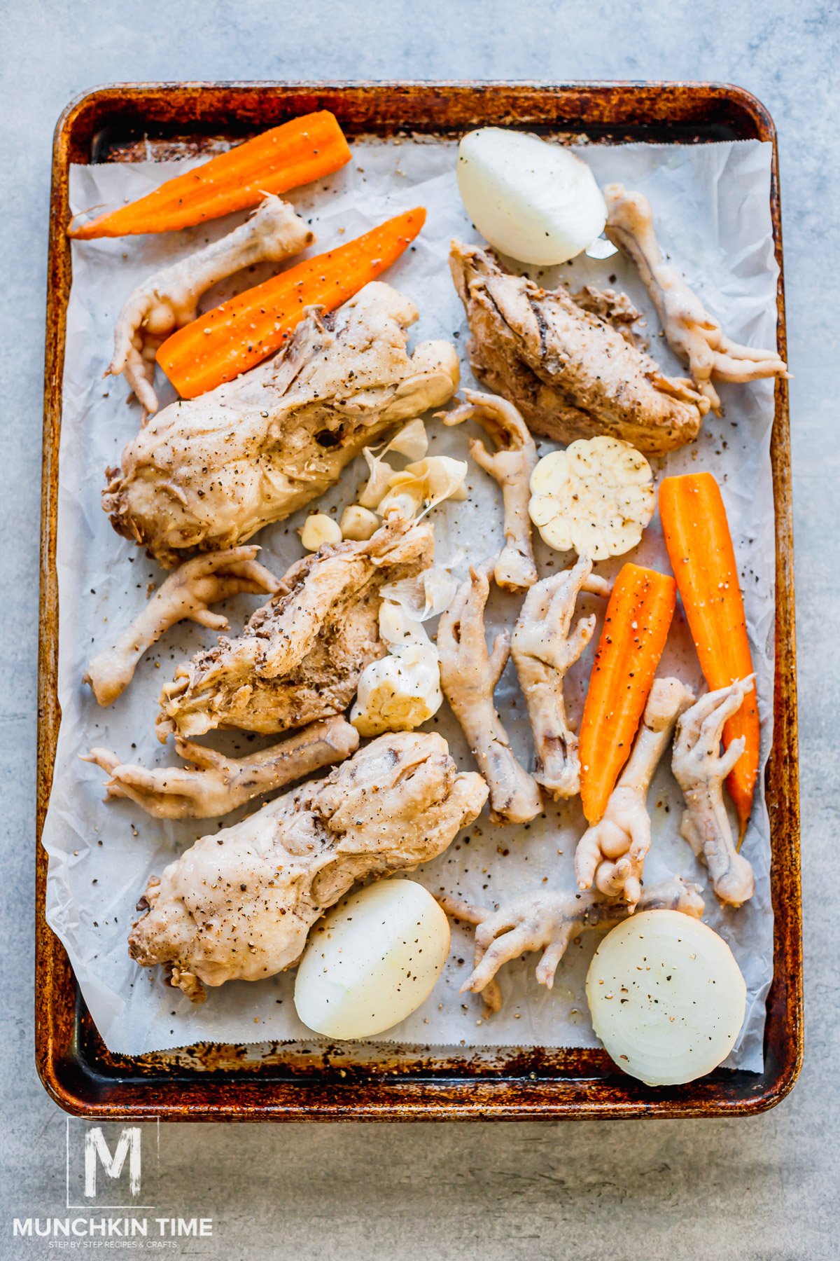 veggies and chicken feet on a parchment paper ready for roasting.
