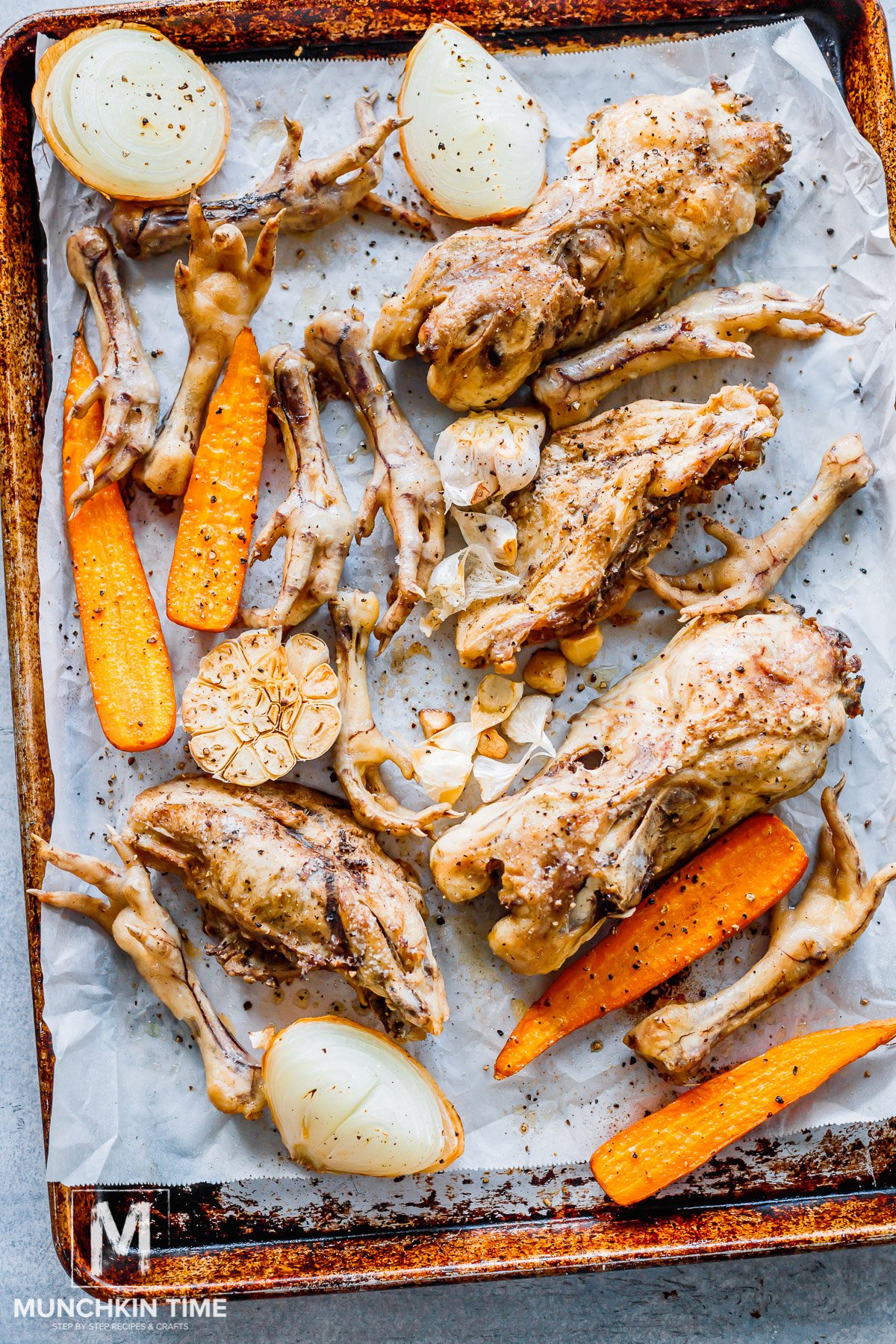 Chicken feet and backs with veggies roasted on a baking sheet.
