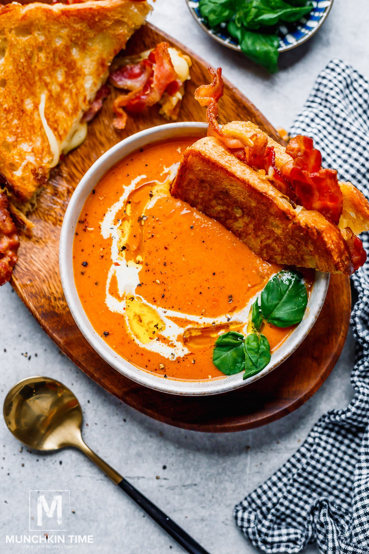 Roasted Tomato Bisque in a bowl with grilled sandwich and basil.