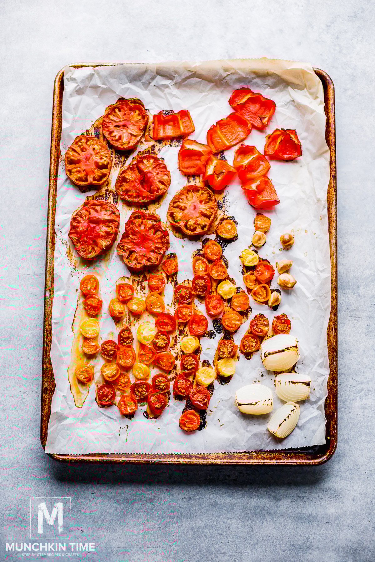 Roasted Tomatoes with onion and garlic on a baking sheet.