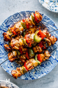 Perfectly Grilled Lemon Garlic Chicken Thighs Skewers on a blue plate.