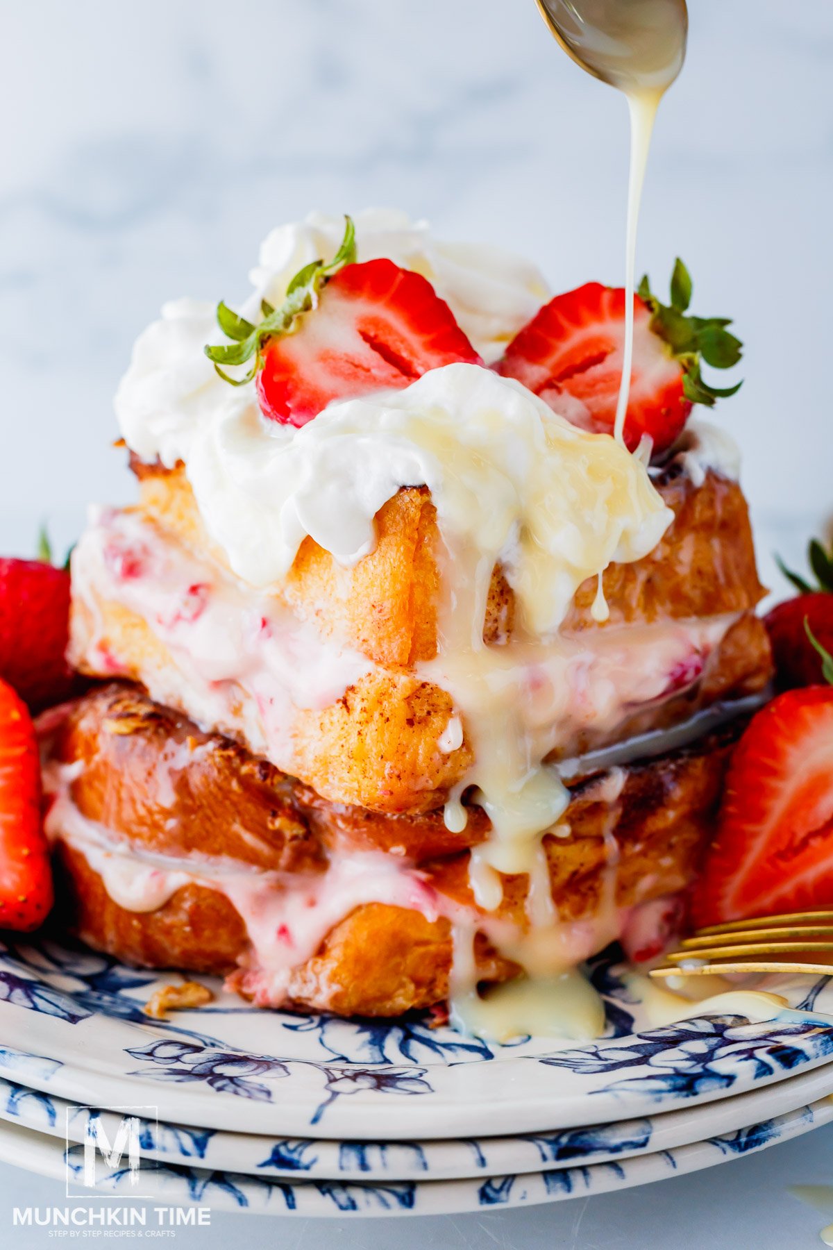 Strawberry Stuffed French Toast with condensed milk pouring over the top.