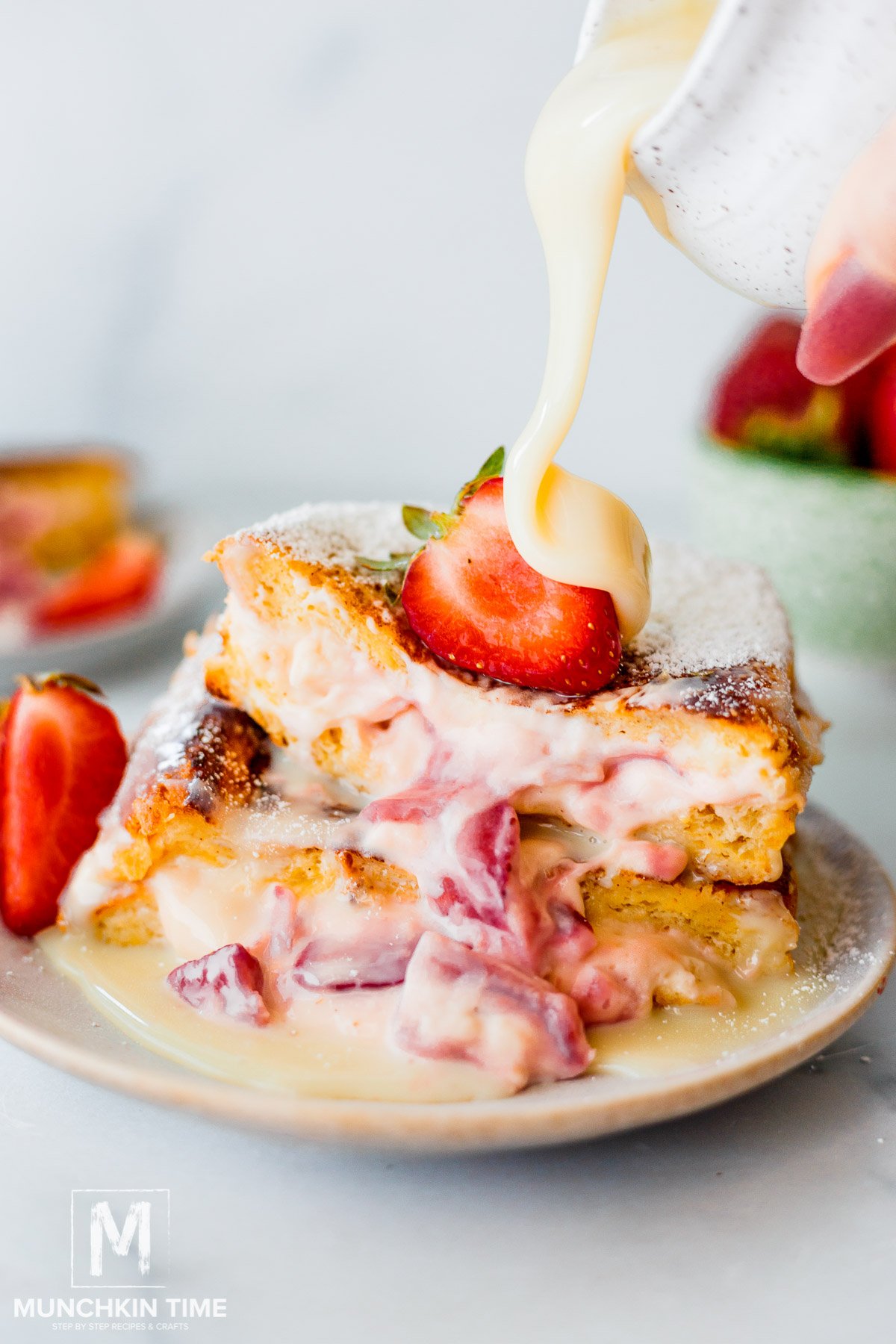 Strawberry Stuffed French Toast with condensed milk pouring over the top.