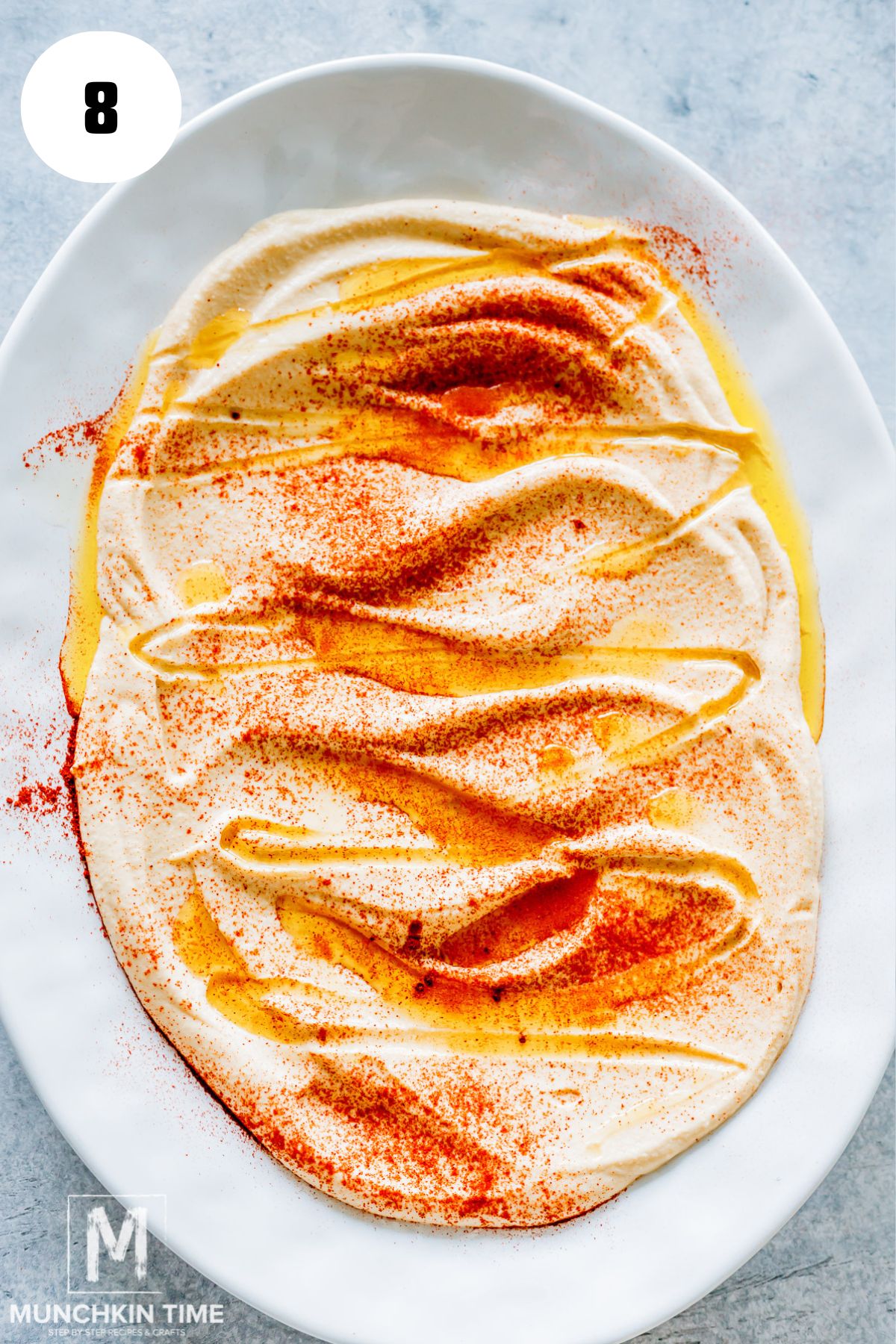 hummus Spread onto a serving platter and drizzled with oil and paprika.