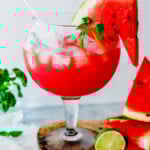 iced watermelon juice garnished with watermelon slice and basil.