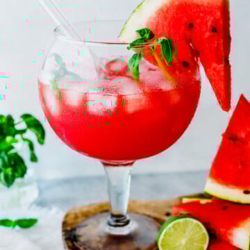 iced watermelon juice garnished with watermelon slice and basil.
