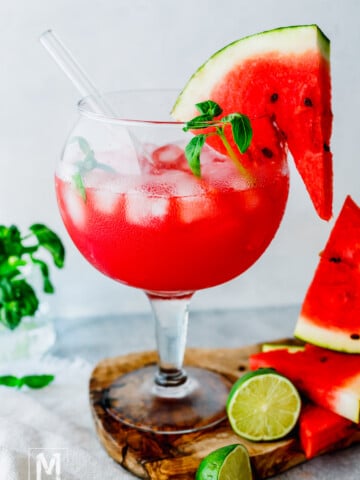 iced watermelon juice garnished with watermelon slice and basil.