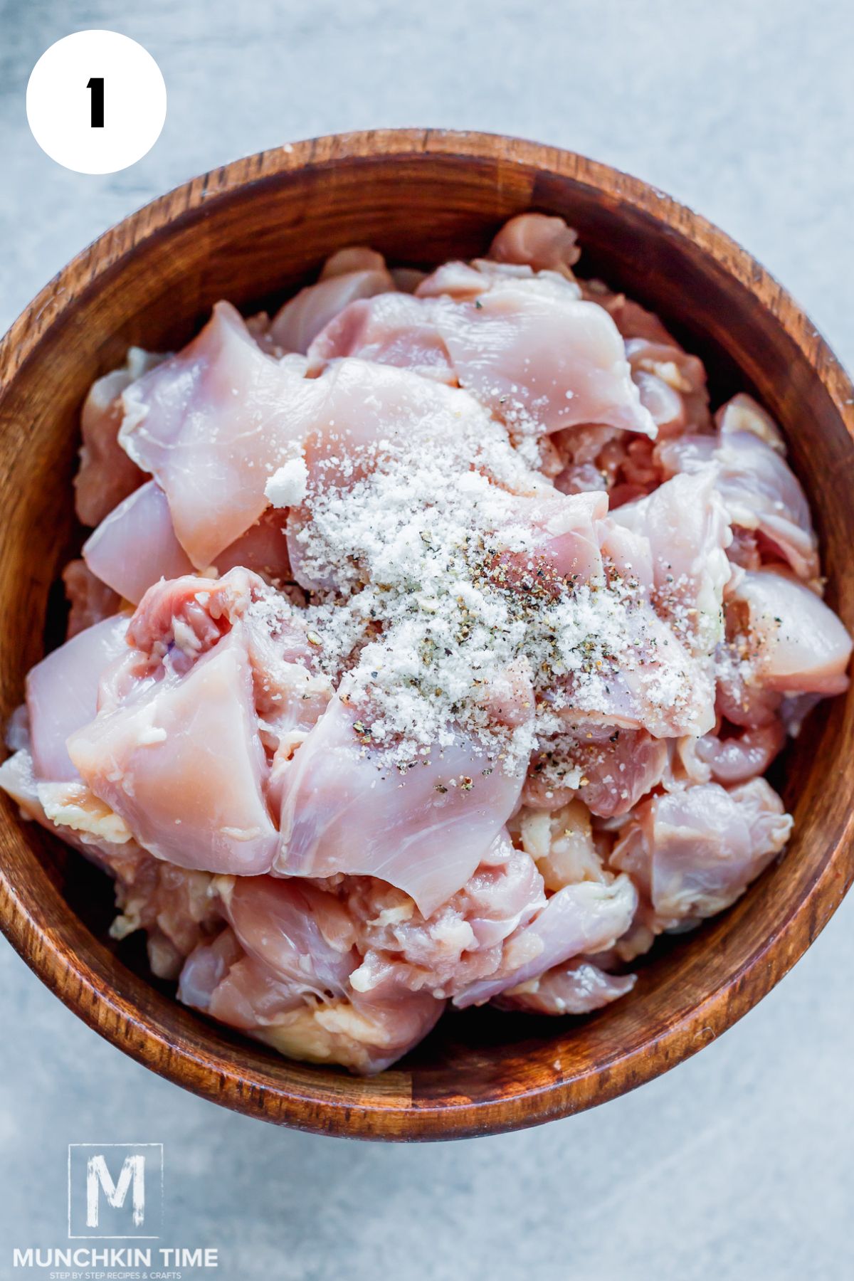 chicken in a bowl with salt and pepper on top.