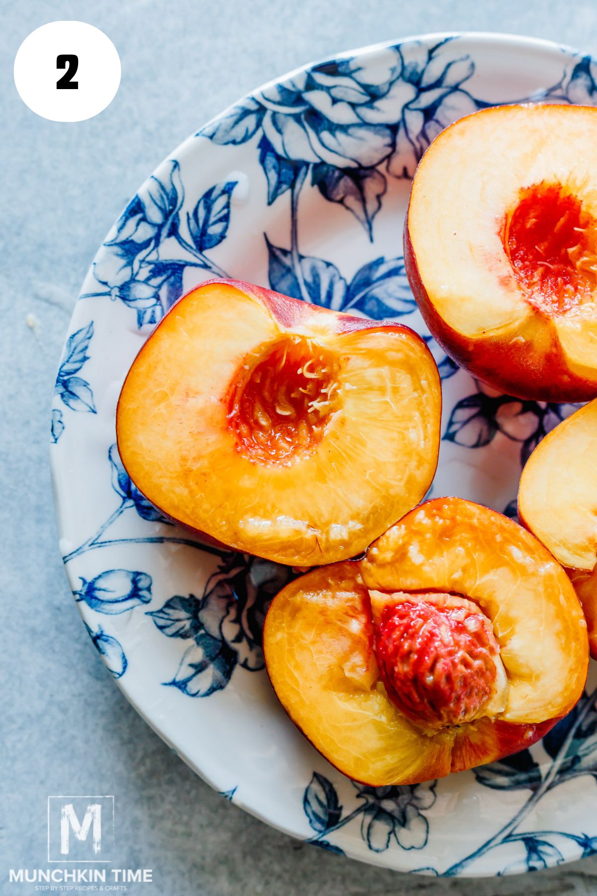 ripe peaches cut in half on a blue English plate.