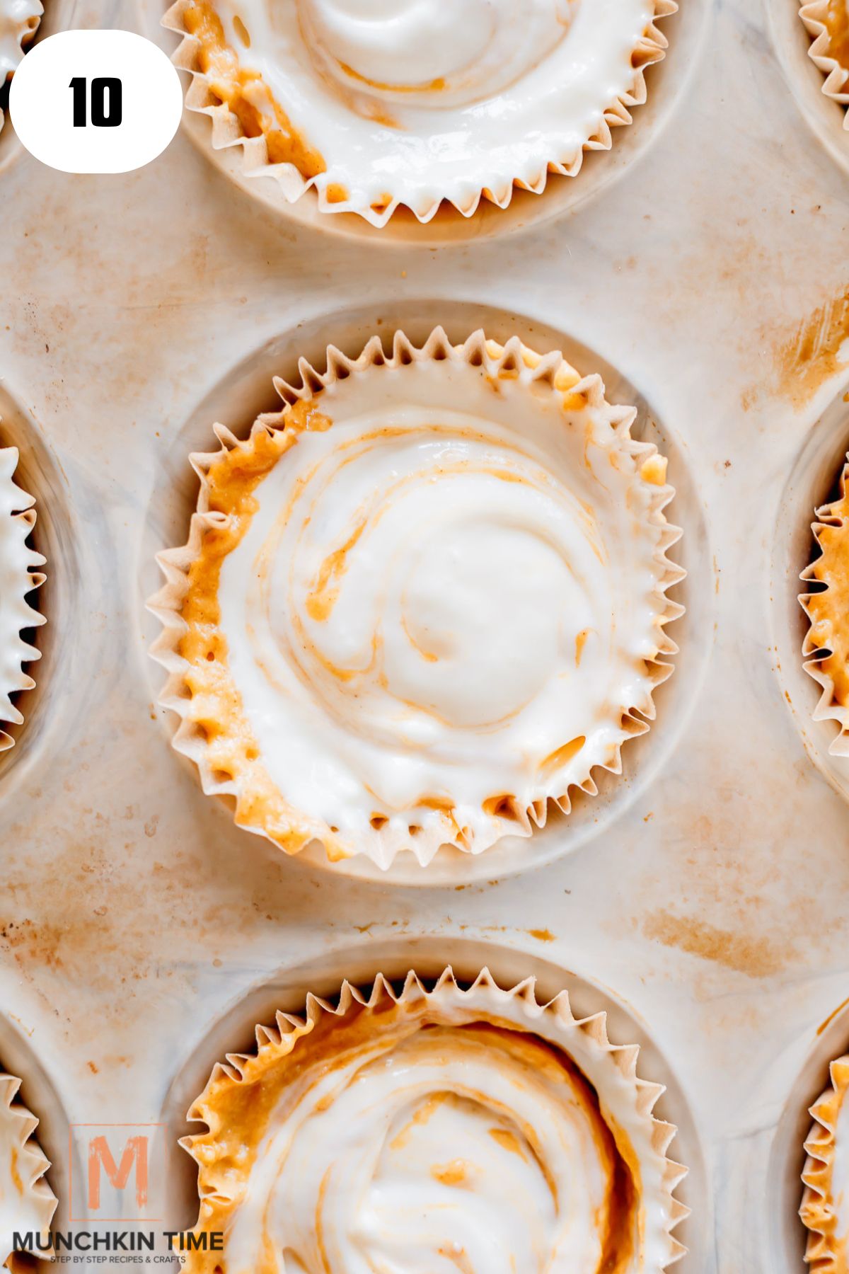 muffin batter in a pan with cream cheese filling on top.
